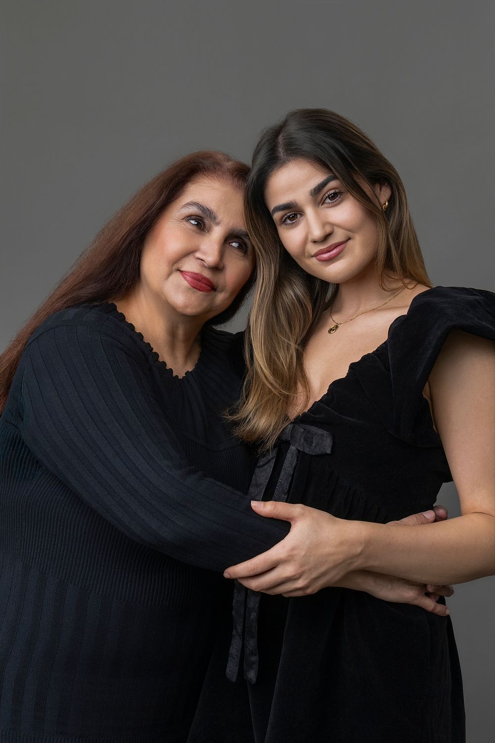 A series of six connected photos showing two people in black outfits posing together against a gray background.