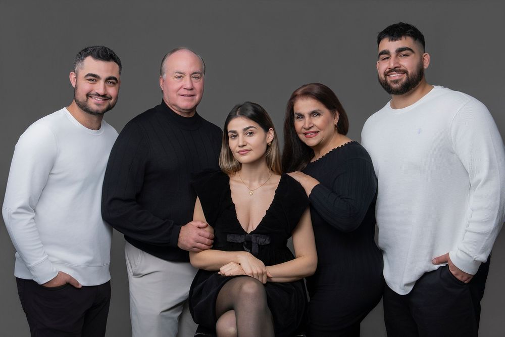 A group of people wearing black and white outfits pose together in a series of professional studio photographs.
