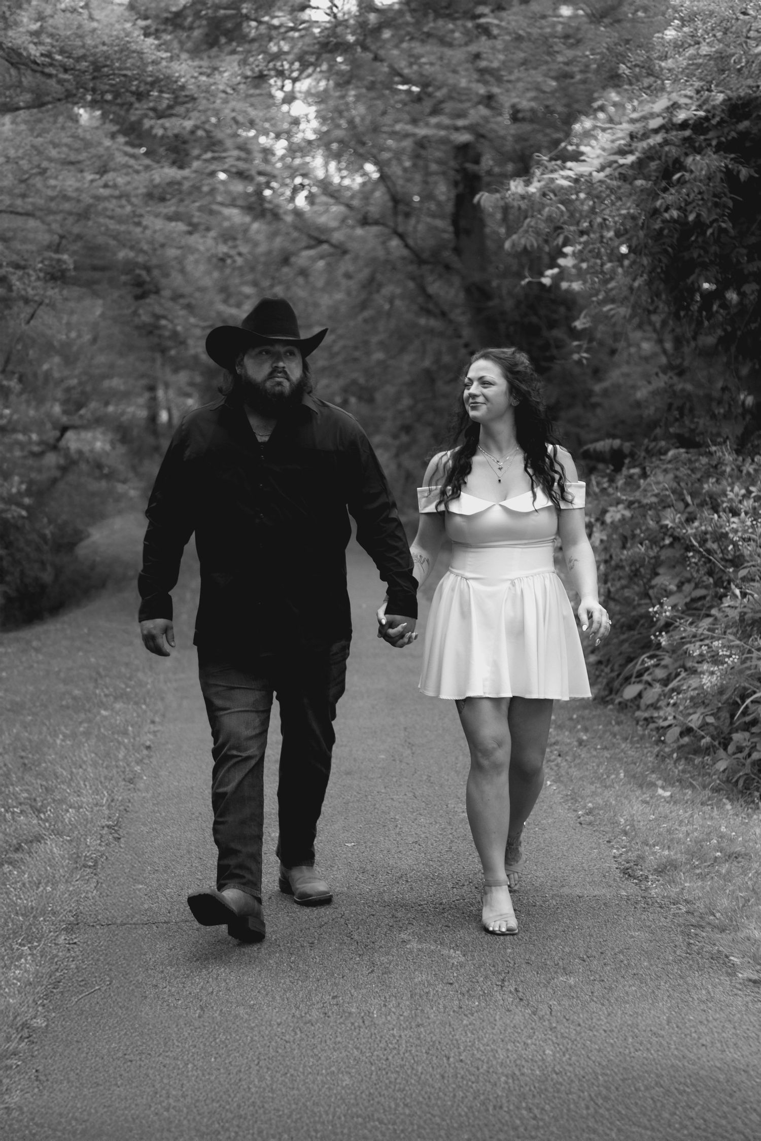 Black and white image sequence of two people walking together on a garden path while holding hands.