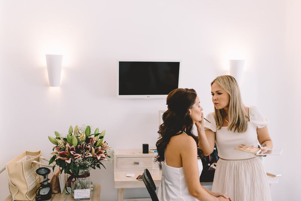 A collection of bridal beauty preparation photos showing makeup application and hair styling in white spaces.