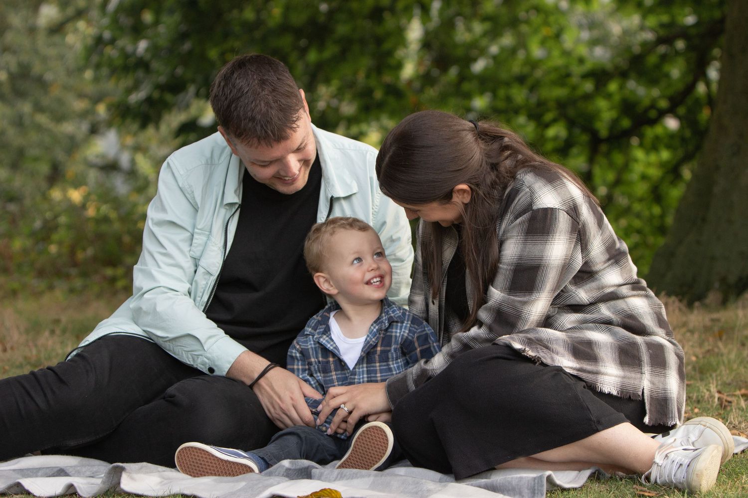A happy family shares a joyful moment together while having a picnic outdoors on a blanket.