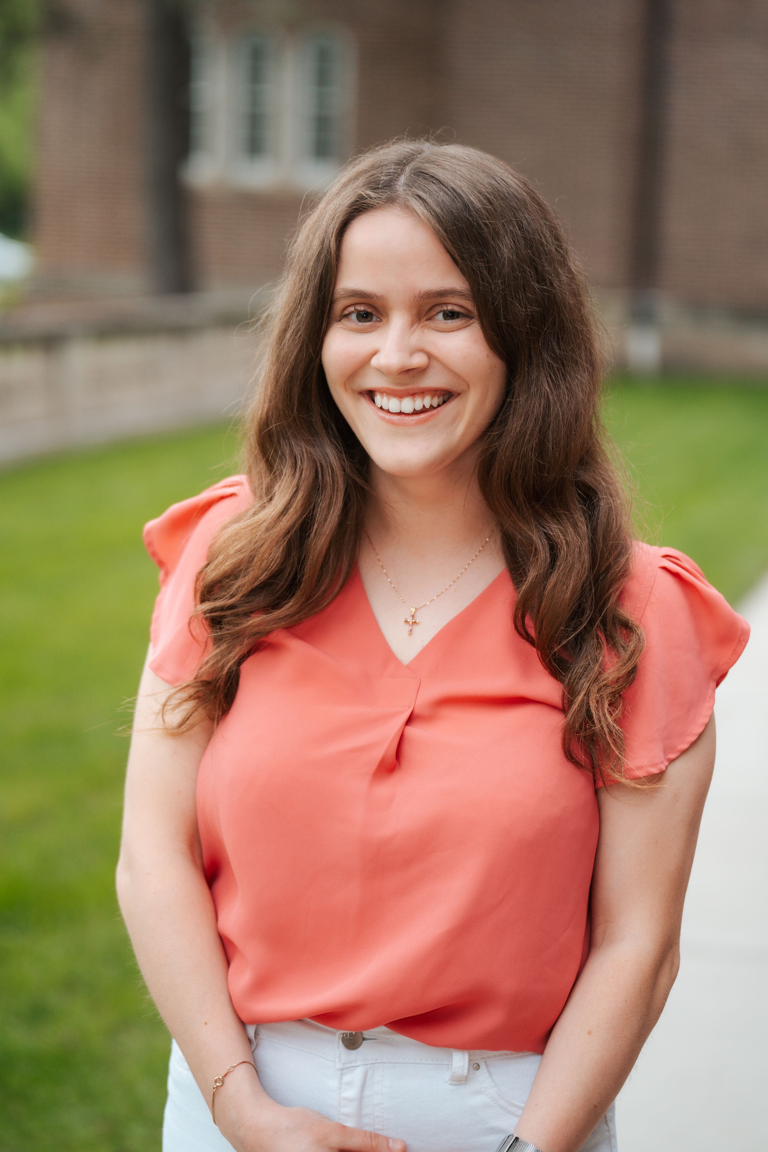 Warm and colorful portrait headshot of Hannah, smiling and laughing at the camera while wearing bright coral in St. Paul, Minnesota.