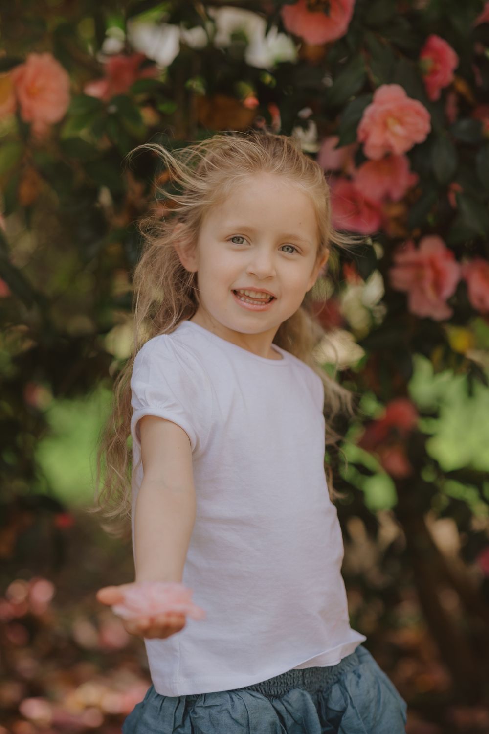 A cheerful outdoor portrait surrounded by blooming coral roses in a garden setting.