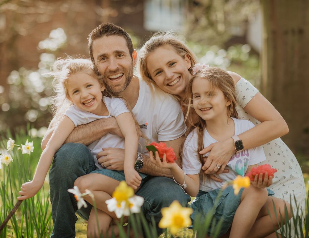A family sits together in a garden with blooming daffodils during springtime.