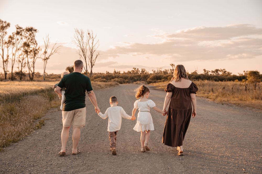 Family walking hand in hand along dirt road