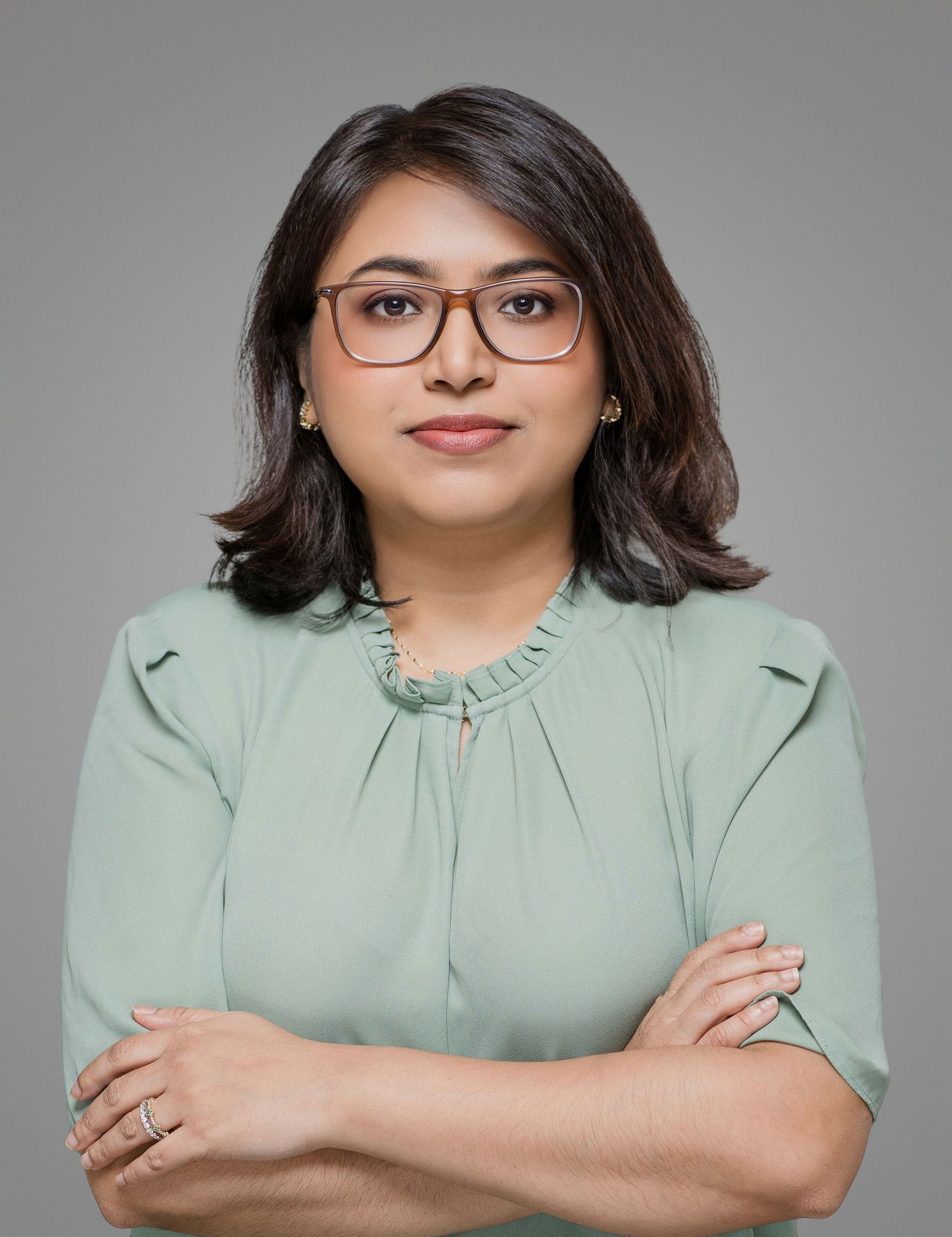 Professional headshot of person in mint green blazer against grey background.