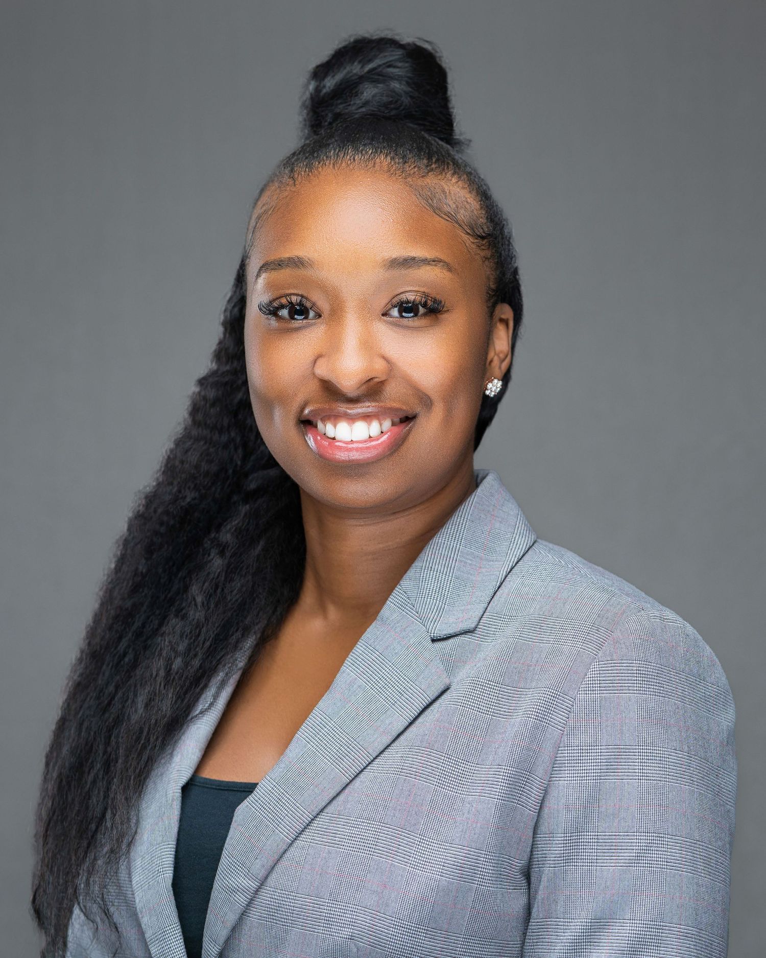Professional portrait in gray blazer against neutral studio background.