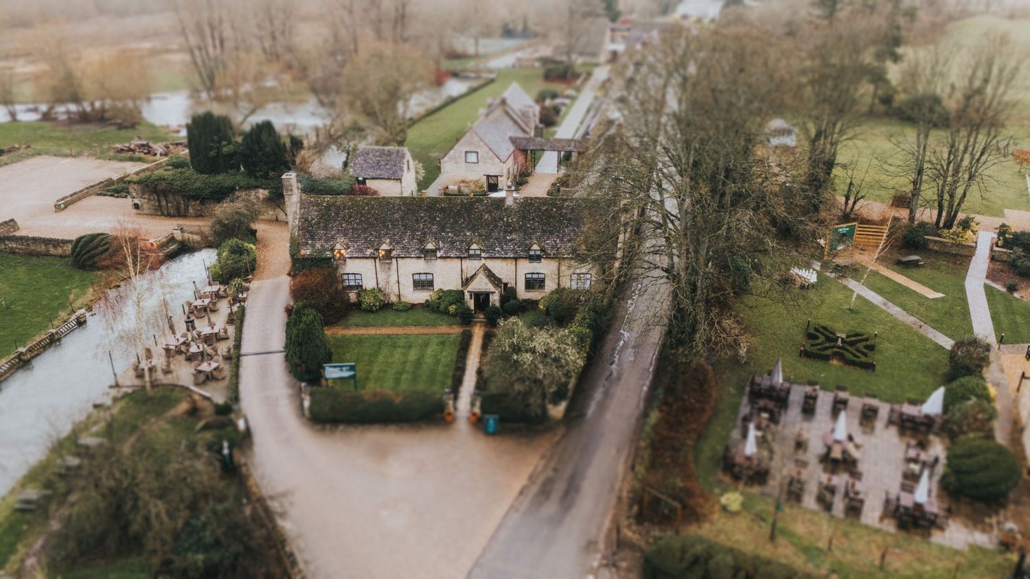 A panoramic aerial view of a residential area with houses, trees, and vegetation during overcast weather.
