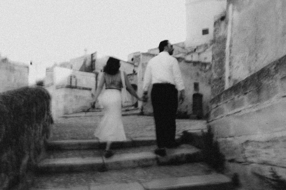 A series of grayscale images showing figures walking and standing in a Grecian-style setting with white buildings.