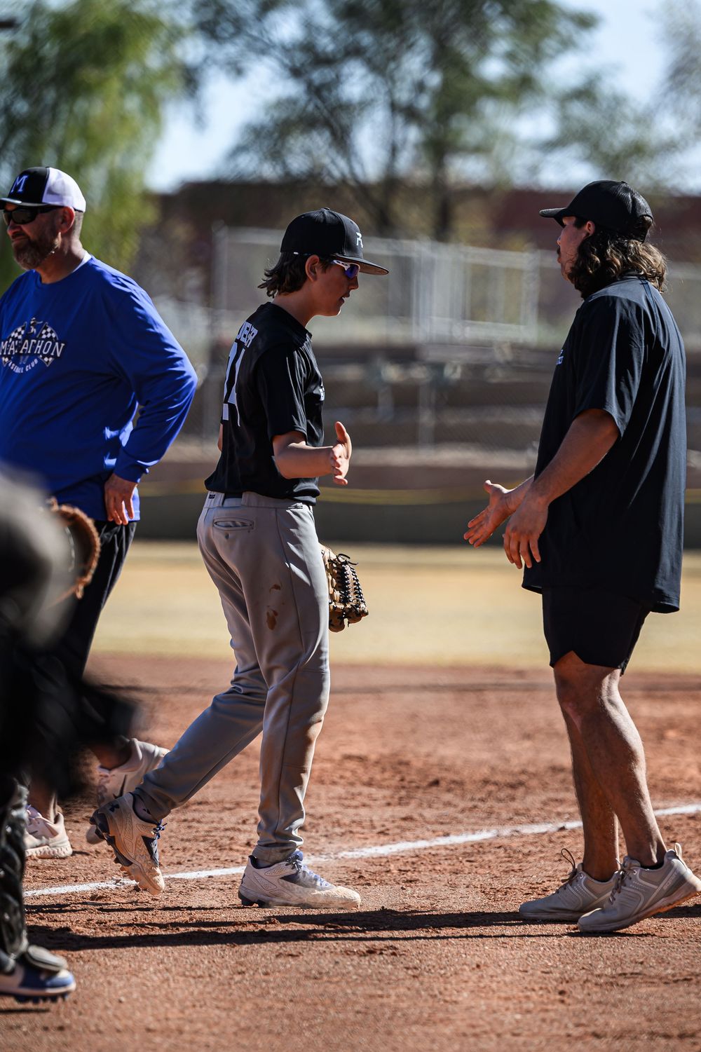 Young PDP Baseball player receives coaching tips between innings during a youth baseball game.