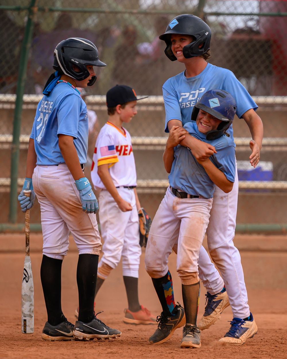 Youth baseball players in blue PDP Baseball uniforms celebrate a run scored during a game.