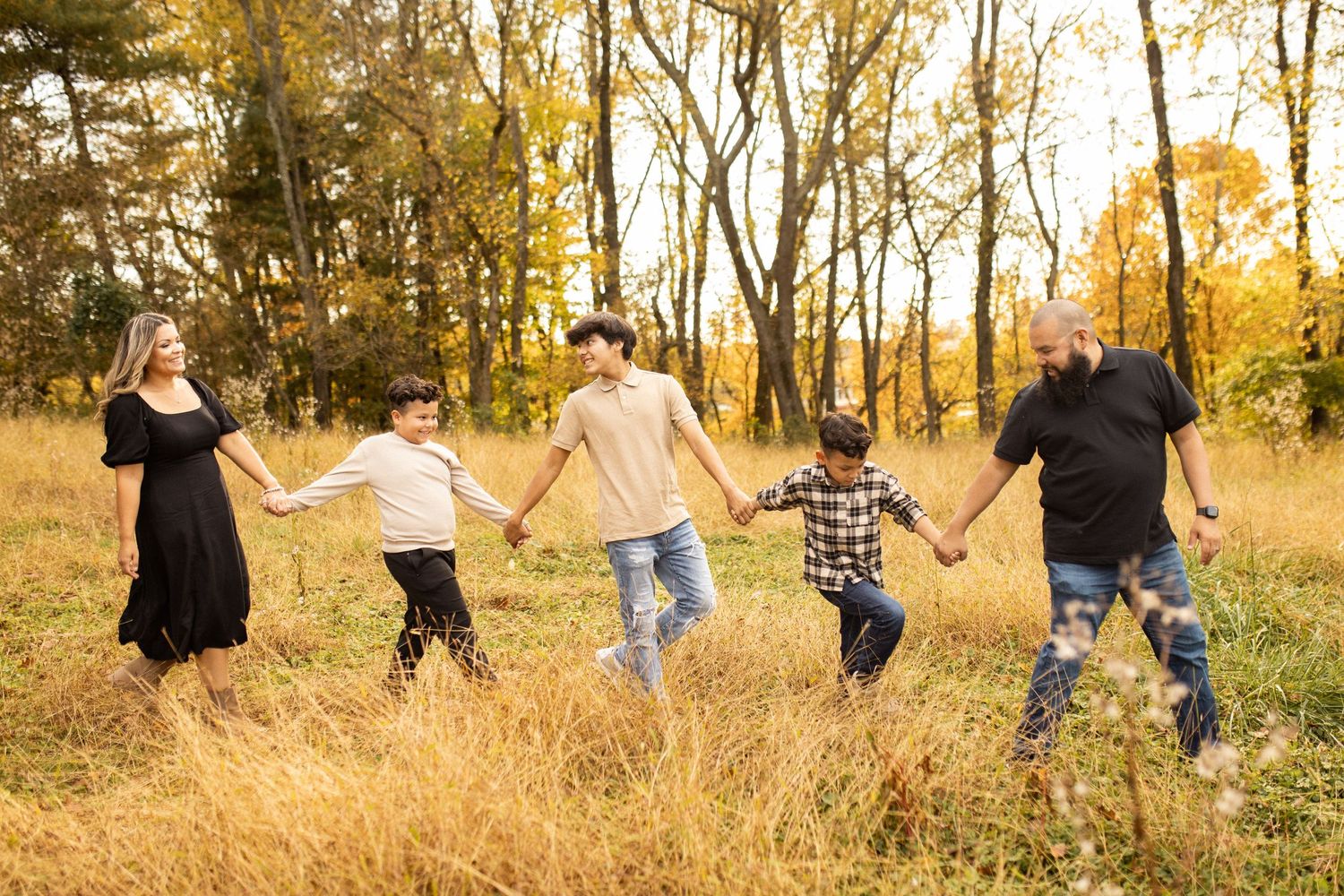 Group runs through golden autumn field during sunset photoshoot.