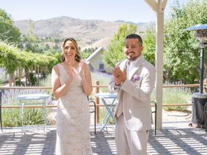Wedding couple shares joyful laughter on sunny porch with mountain views in the background.
