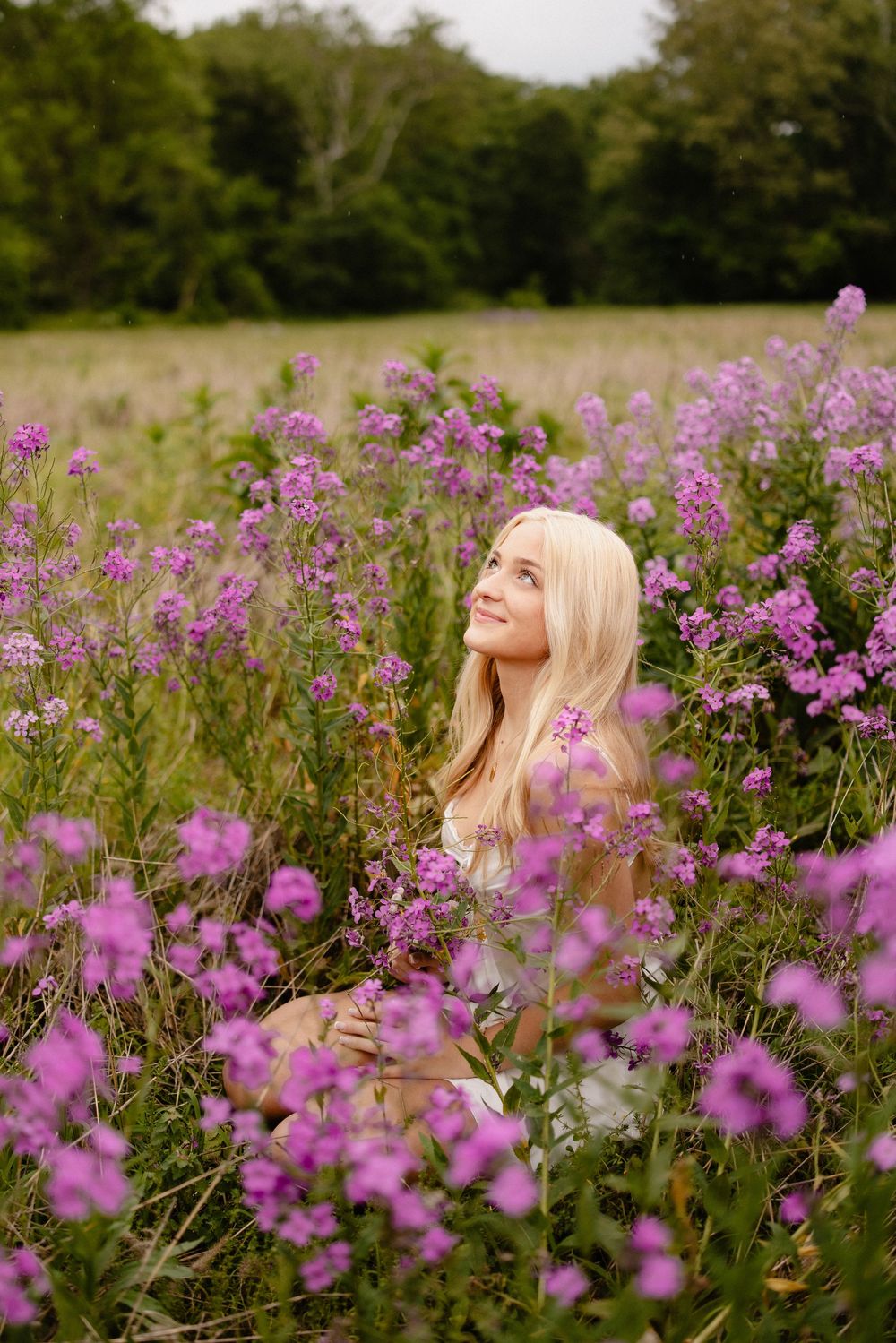 A nature-inspired portrait surrounded by blooming purple wildflowers in a summer meadow.