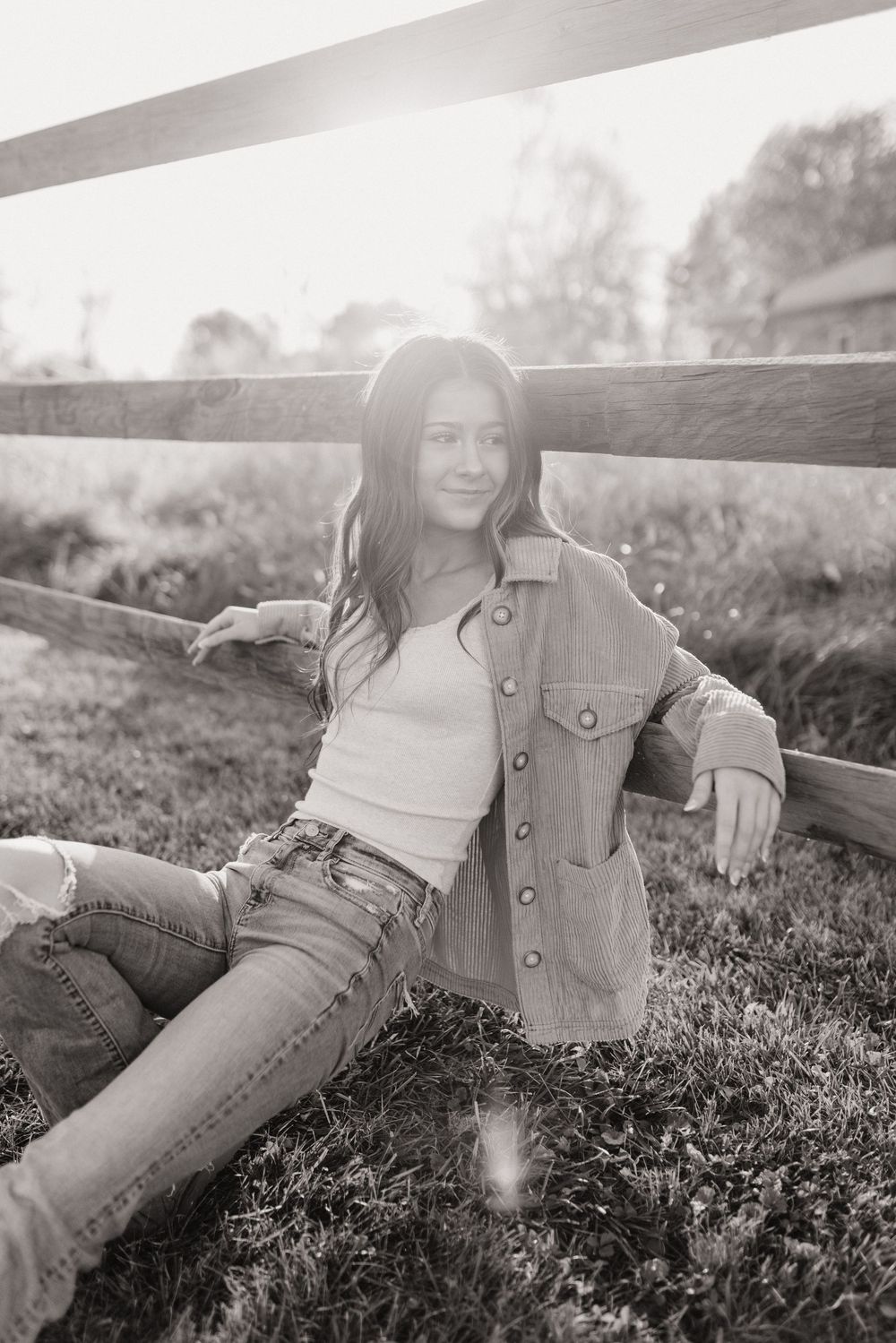 A casual portrait against a wooden fence wearing denim and a utility jacket.