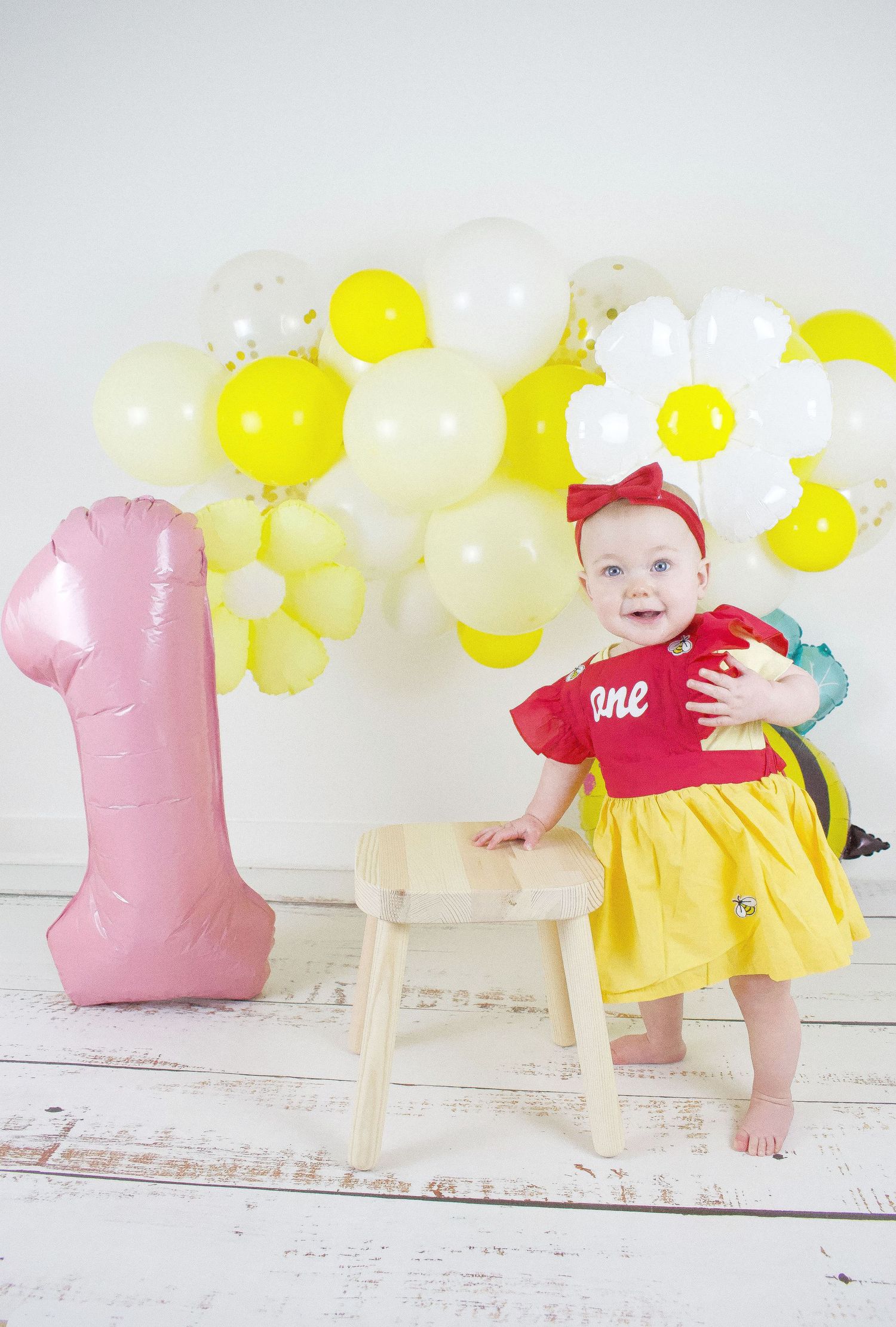 Pink tulle dress and balloons create magical first birthday photo setup.