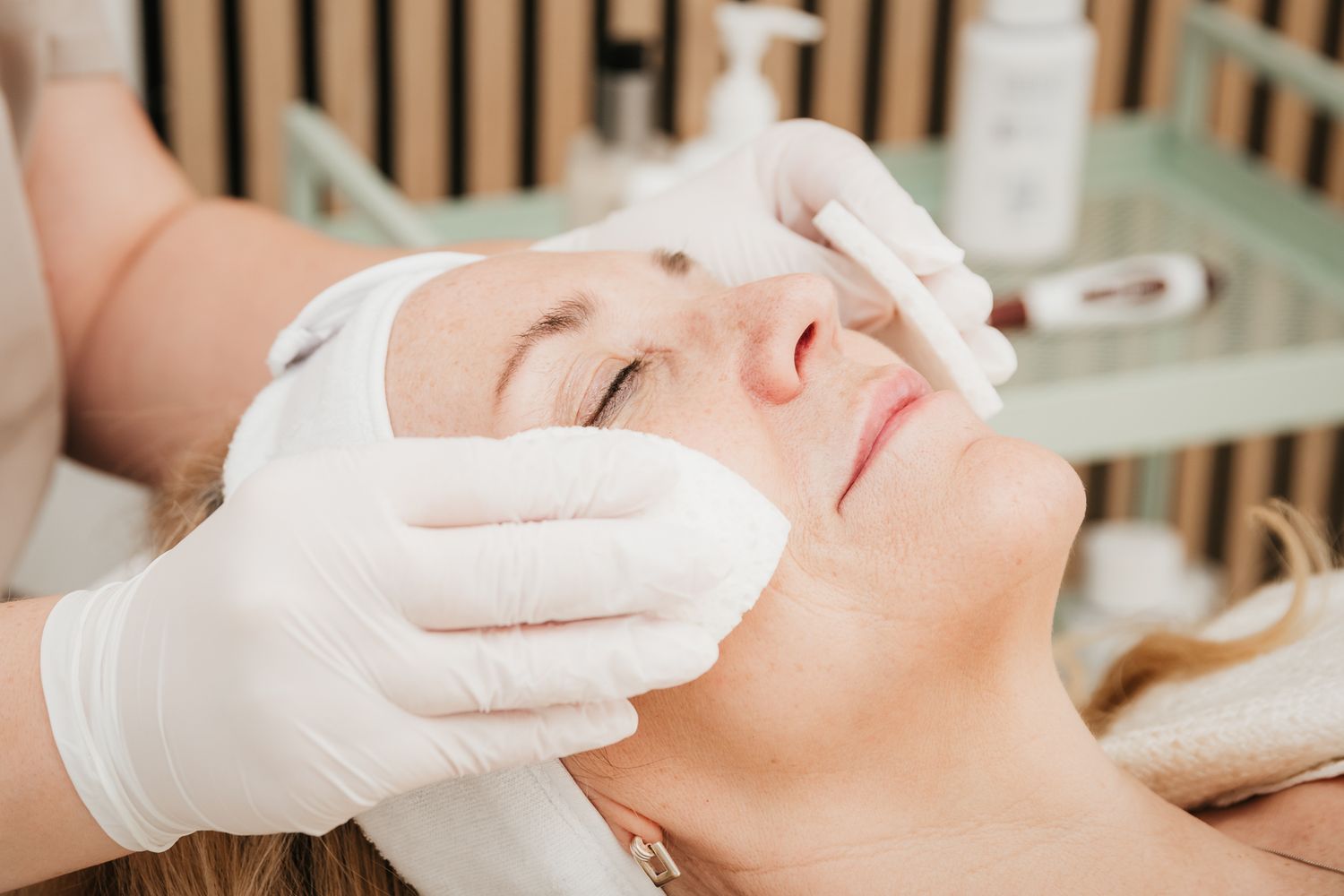 Professional receiving a skincare or facial treatment with white gloved hands performing a gentle procedure.