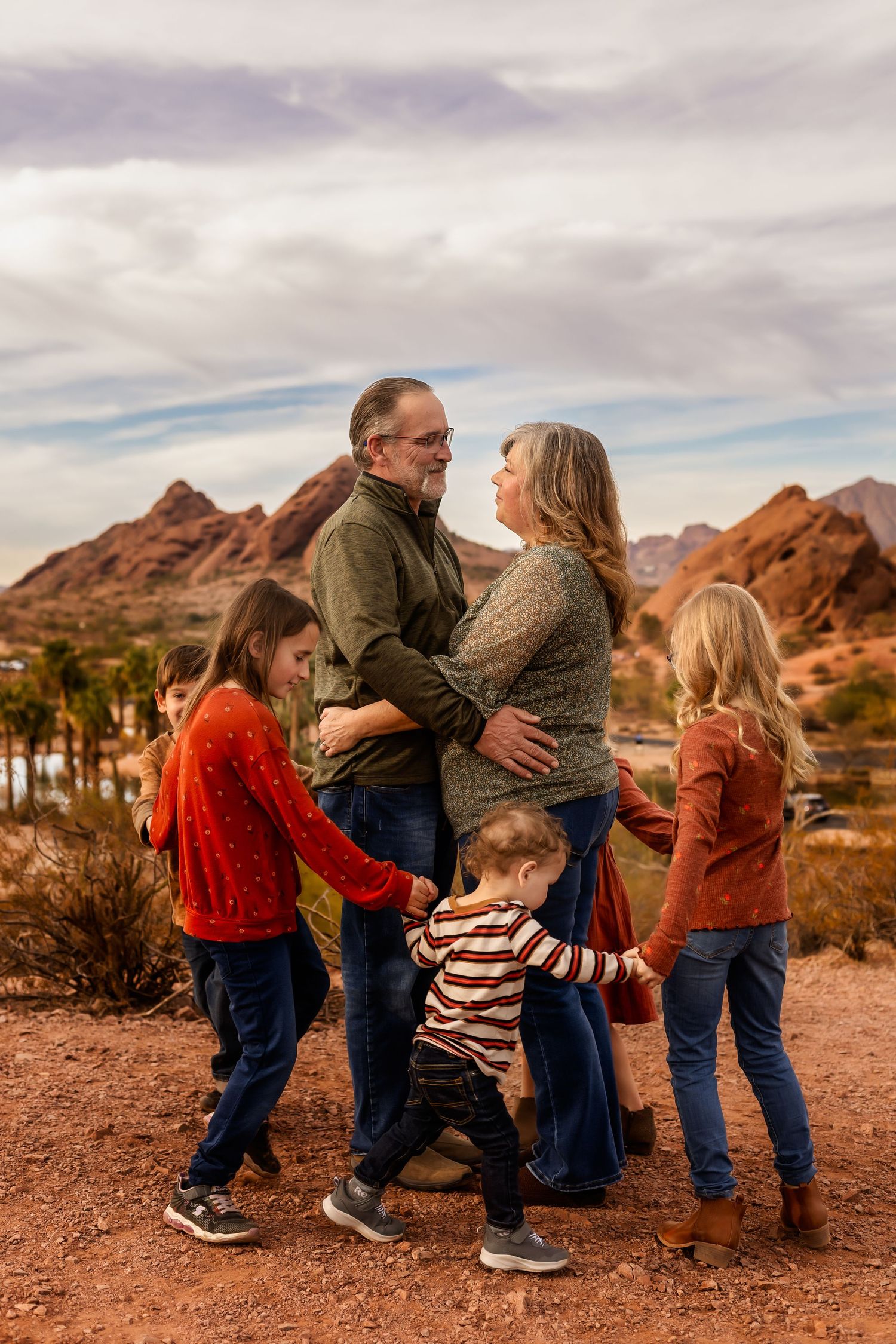 Family enjoying outdoor adventure together against backdrop of red rock mountains and desert landscape at sunset.