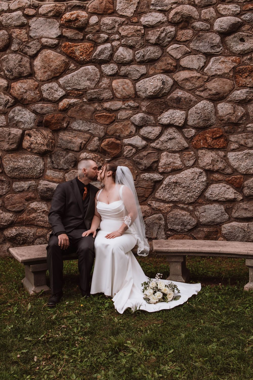 Bride and groom sitting together outside of historic stone church upstate NY