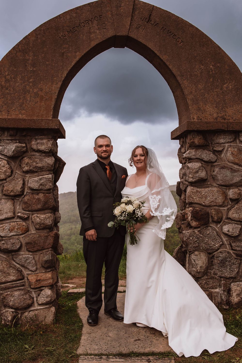 Bride and groom standing together for portraits in front of minnewaska mountains at cragsmoor stone church HVNY