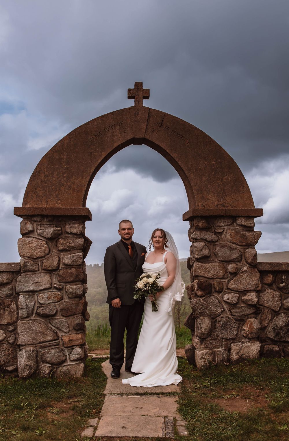 Bride and groom standing together for portraits in front of minnewaska mountains at cragsmoor stone church HVNY