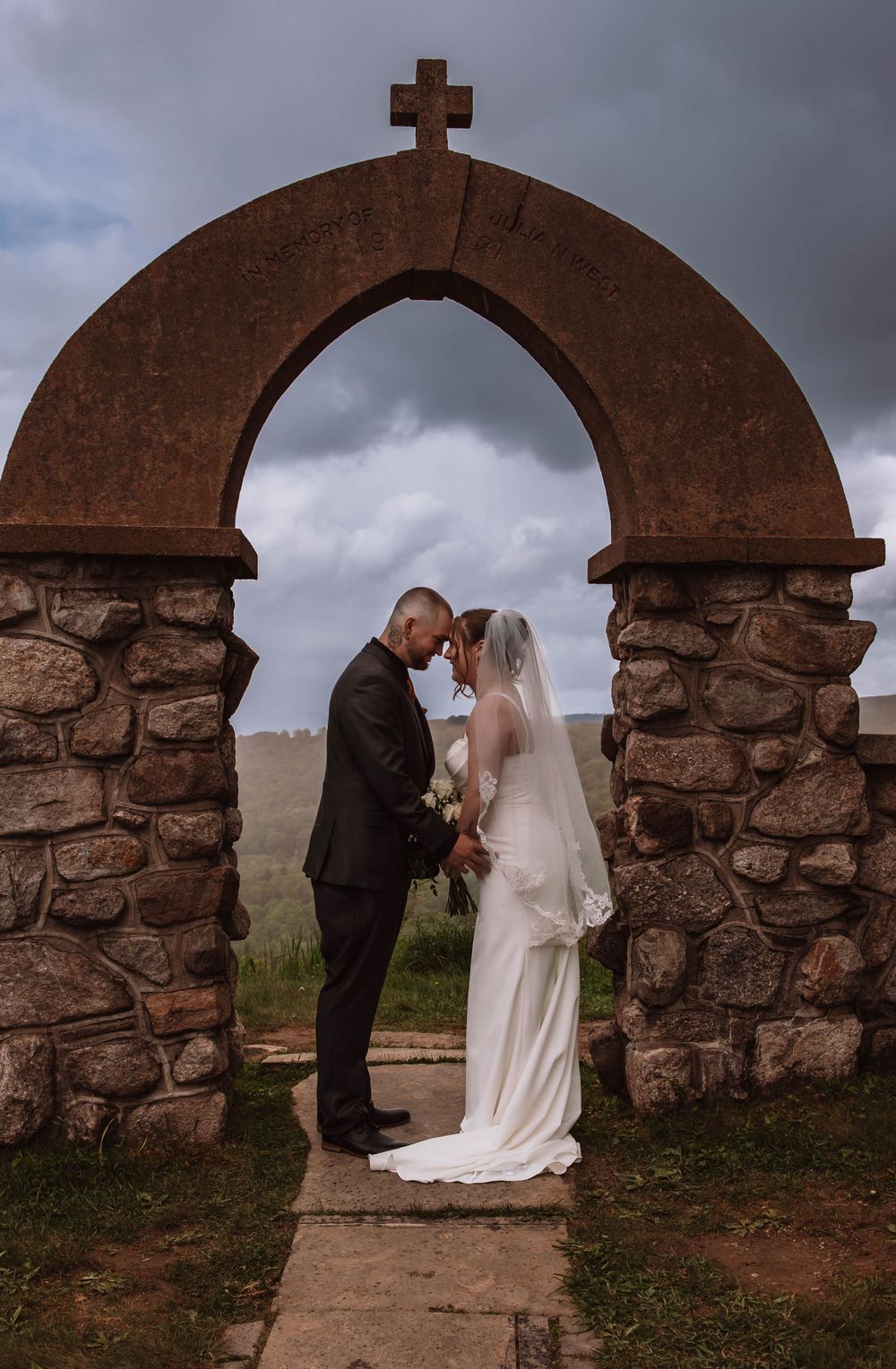 Bride and groom standing together for portraits in front of minnewaska mountains at cragsmoor stone church HVNY