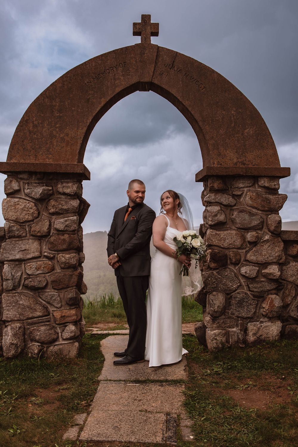 Bride and groom standing together for portraits in front of minnewaska mountains at cragsmoor stone church HVNY