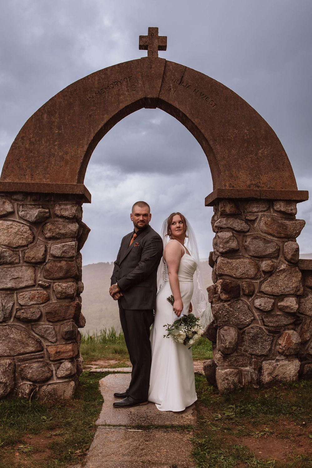 Bride and groom standing together for portraits in front of minnewaska mountains at cragsmoor stone church HVNY