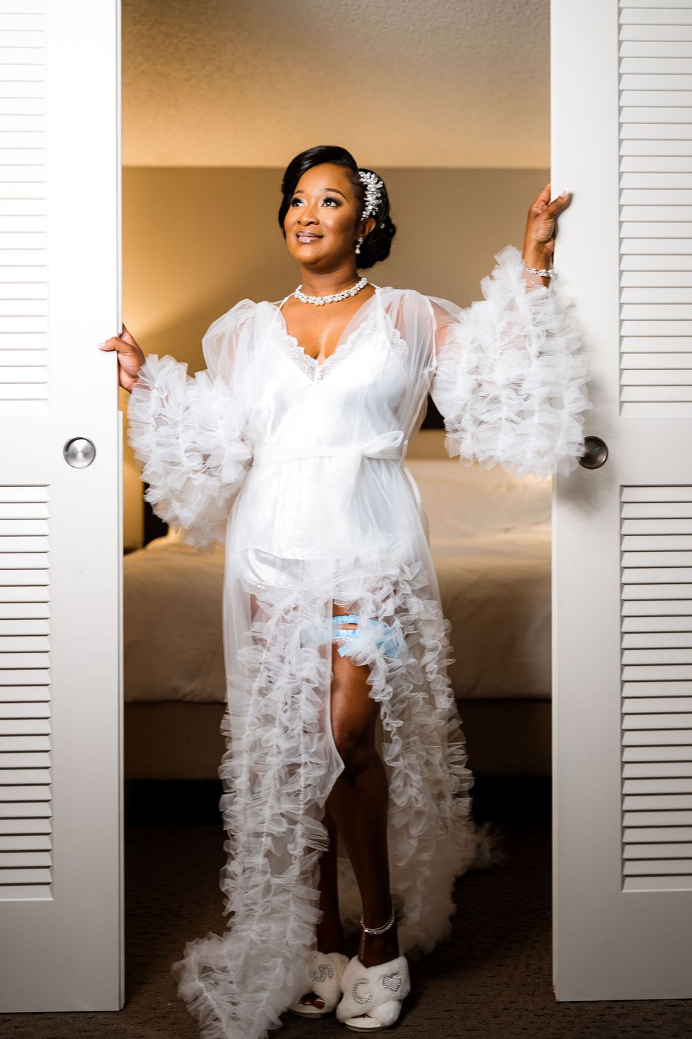 Elegant white ruffled robe with flowing tulle details and sneakers styled in a bridal boudoir setting.