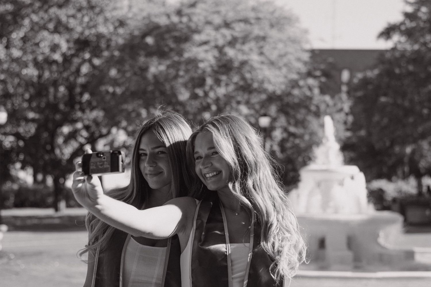 Two FSU graduates taking a selfie on a disposable camera in front of the famous Westcott fountain.