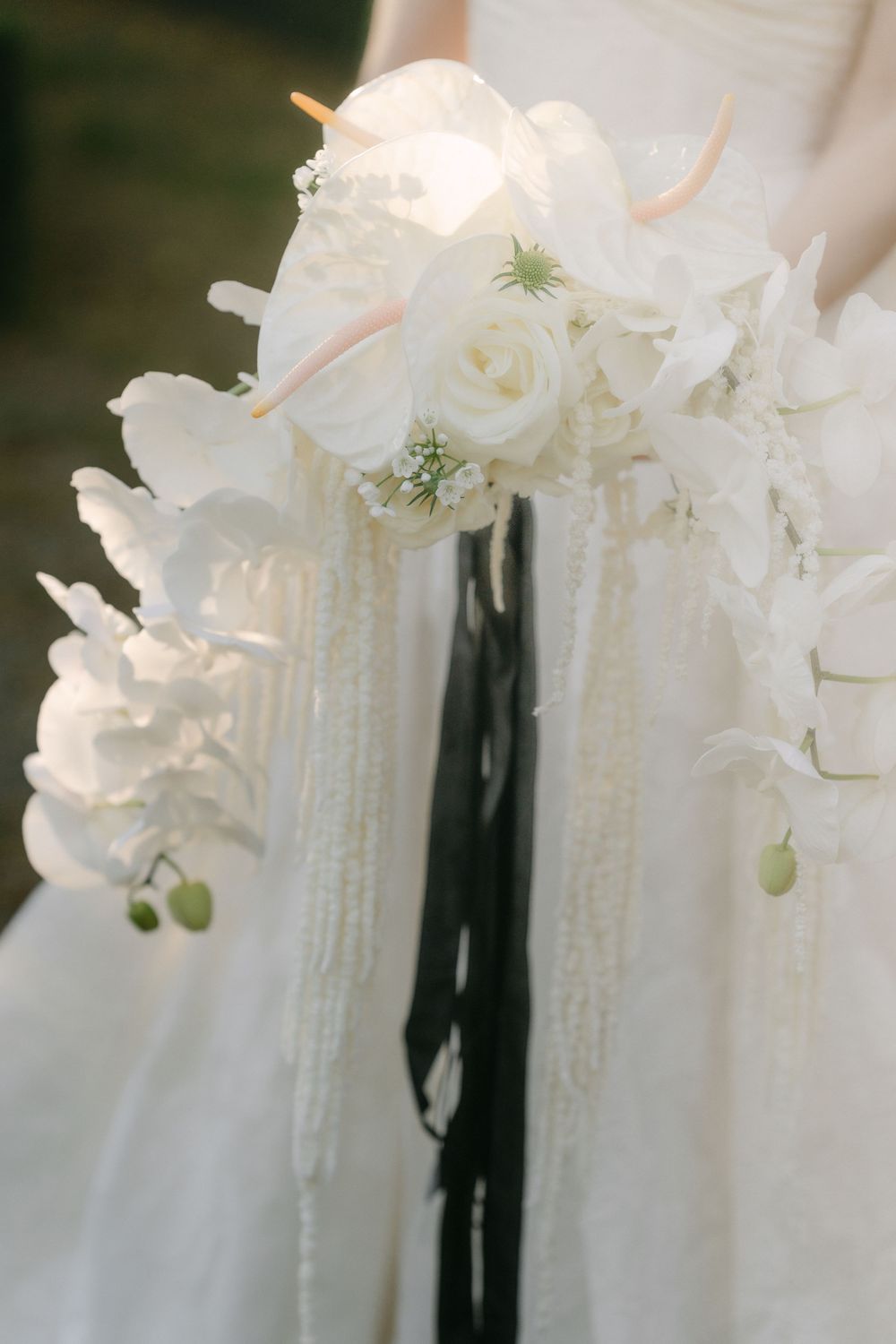 Elegant white roses and cascading pearls decorate a wedding dress with delicate floral arrangements and soft tulle fabric.