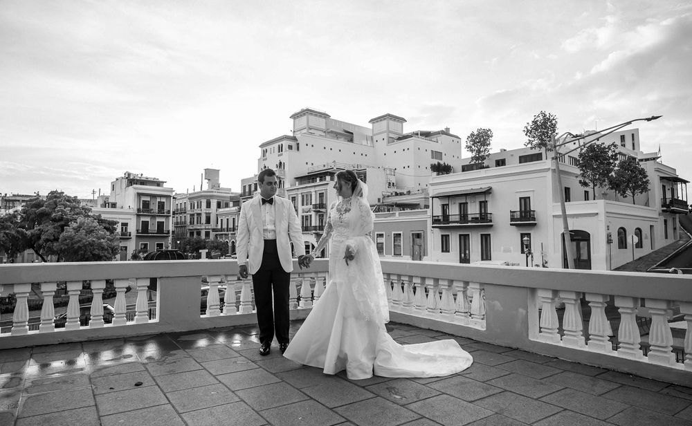 Black and white city rooftop view showing classical architecture with a balcony and ornate balustrade overlooking buildings.