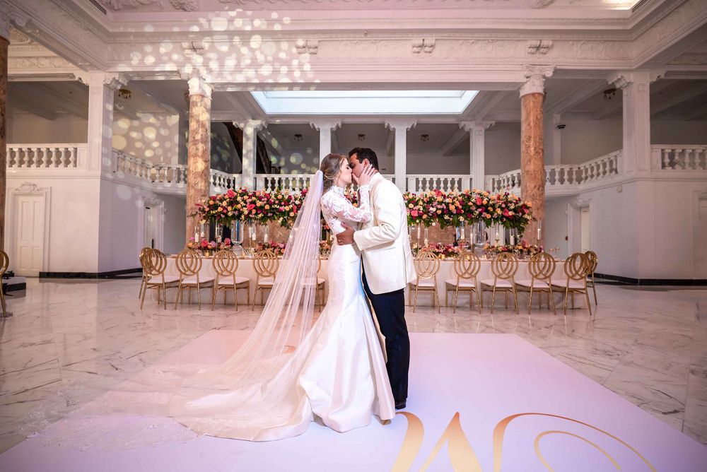A romantic wedding moment in an elegant white ballroom adorned with floral decorations and crystal chandeliers.