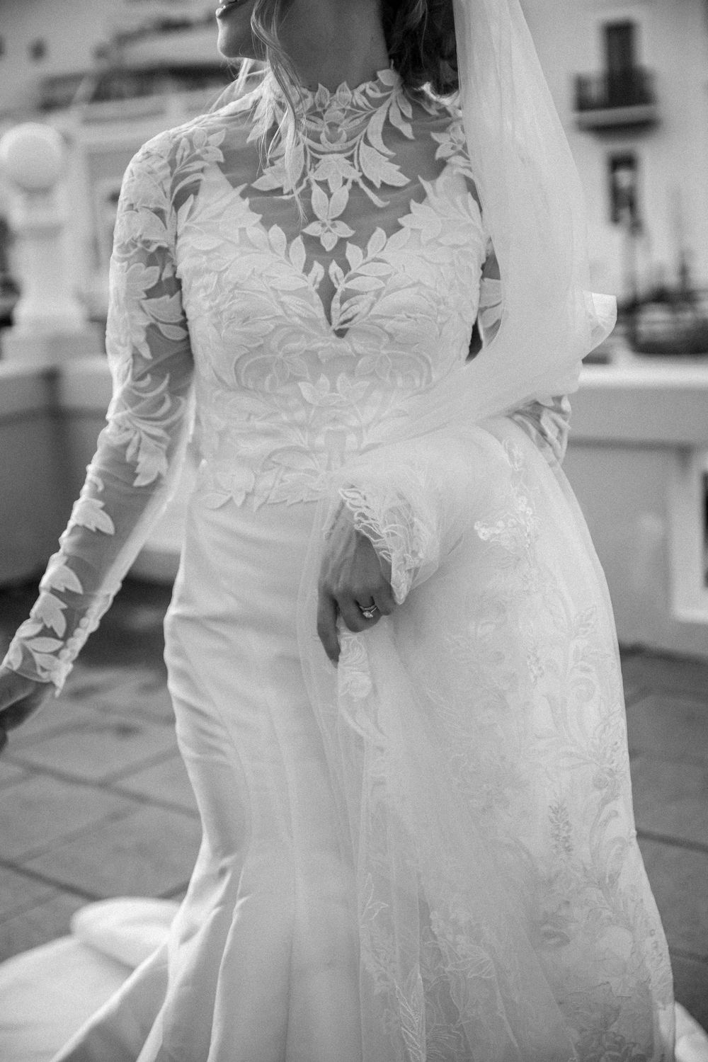 Black and white close-up shots showcase intricate lace details of a flowing wedding gown with long sleeves.