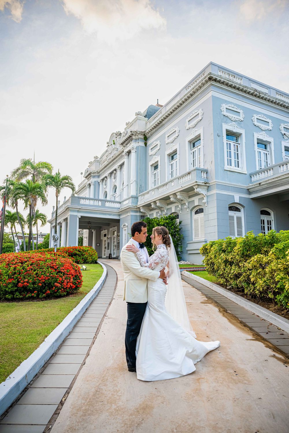 Elegant wedding photos at a grand mansion with light blue exterior, manicured gardens and palm trees in Guayaquil.