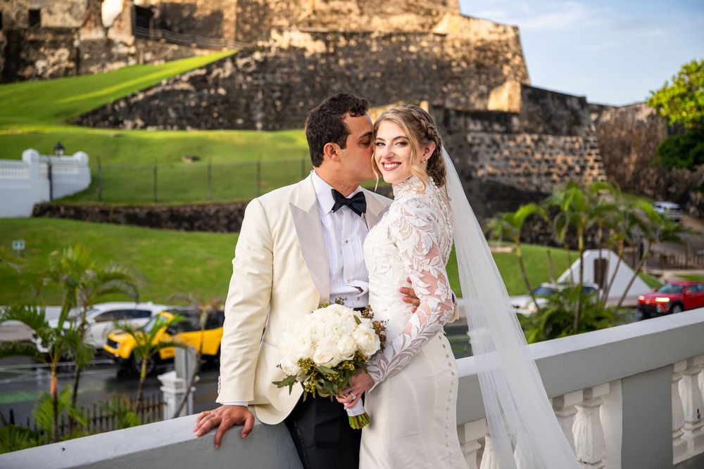 A romantic wedding portrait captured in front of historic stone castle walls with lush green grounds in the background.