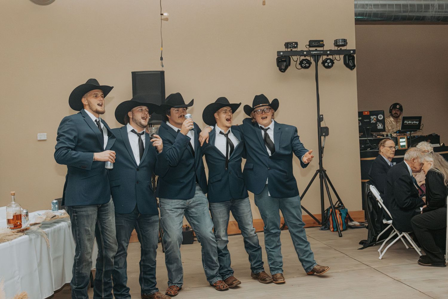 A group of performers in matching black western attire stand together on stage during an event.