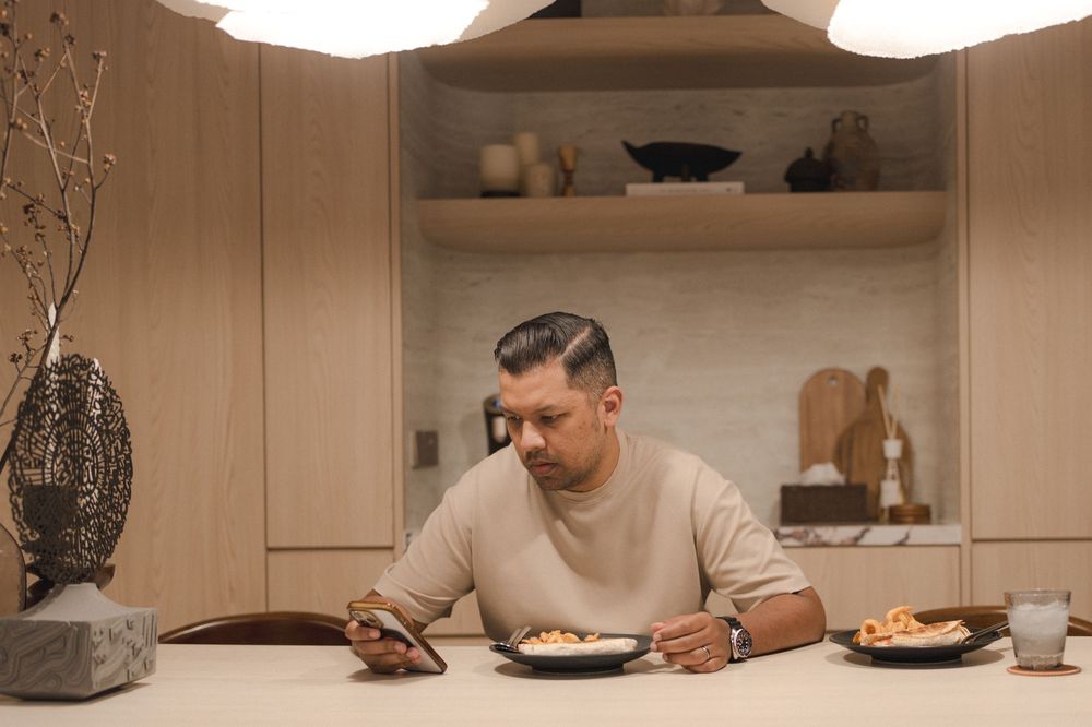 Person eating a meal alone at a kitchen counter with warm lighting and modern interior decor.