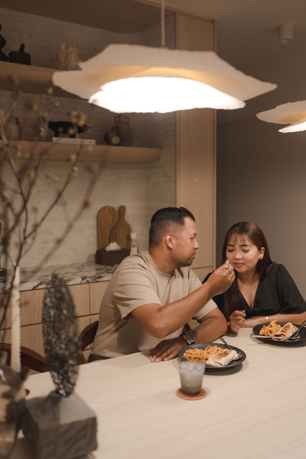 Couple enjoying dinner together at a cozy modern dining table under warm pendant lighting.