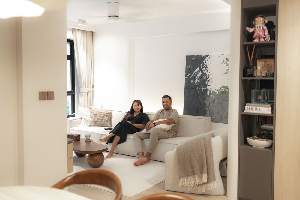Two people relaxing on a white sofa in a bright modern living room with minimalist decor.
