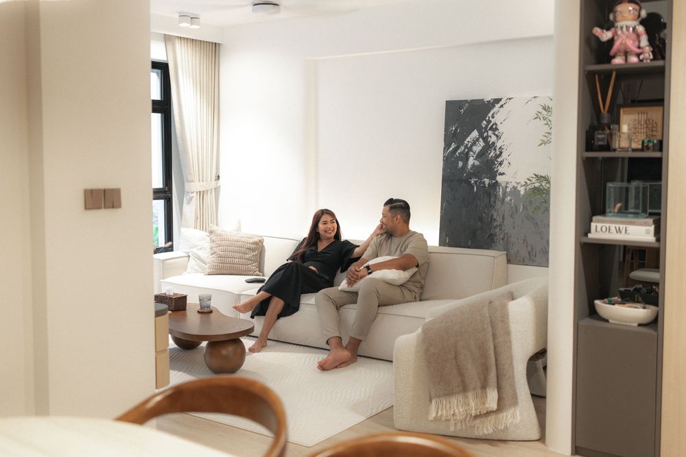 Contemporary living room interior with white couch, throw blanket, abstract wall art and wooden accents.