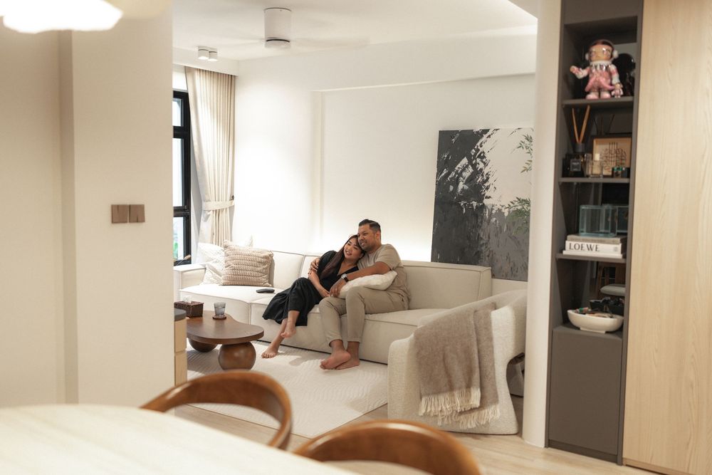 A cozy modern living room interior with a white sofa, built-in shelving, and warm lighting.