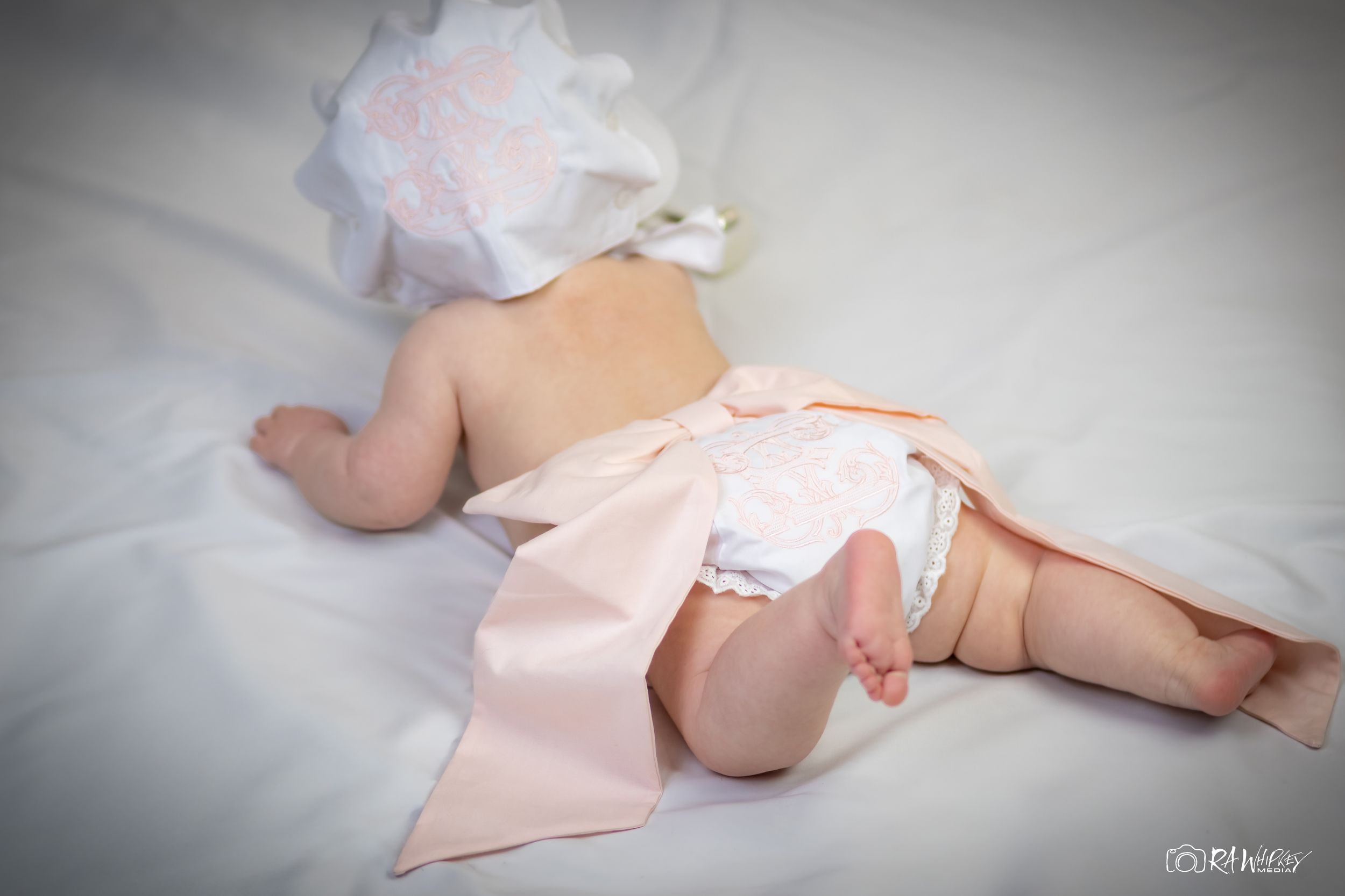 Artistic baby photography setup with soft pink and white elements.
