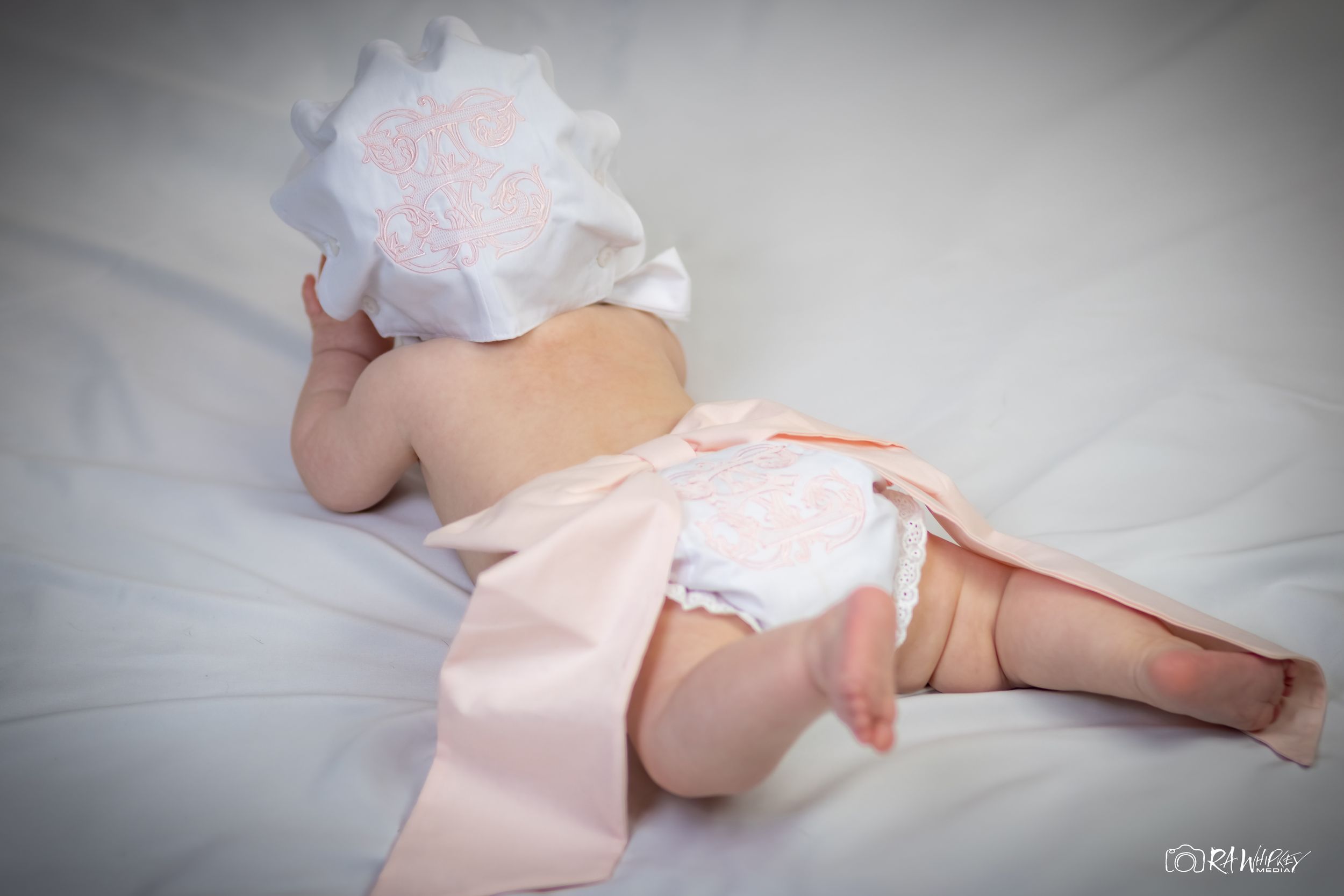 Artistic baby photography composition with soft lighting and pink elements.