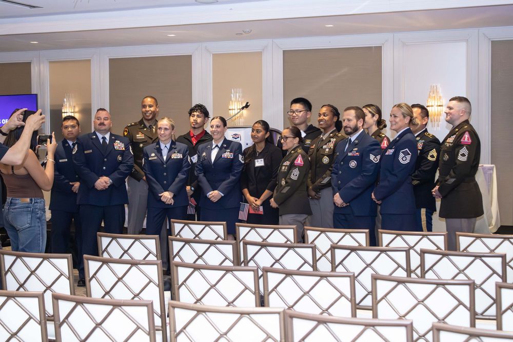 Military personnel in uniform pose together for a group photo at a formal indoor ceremony or awards event.