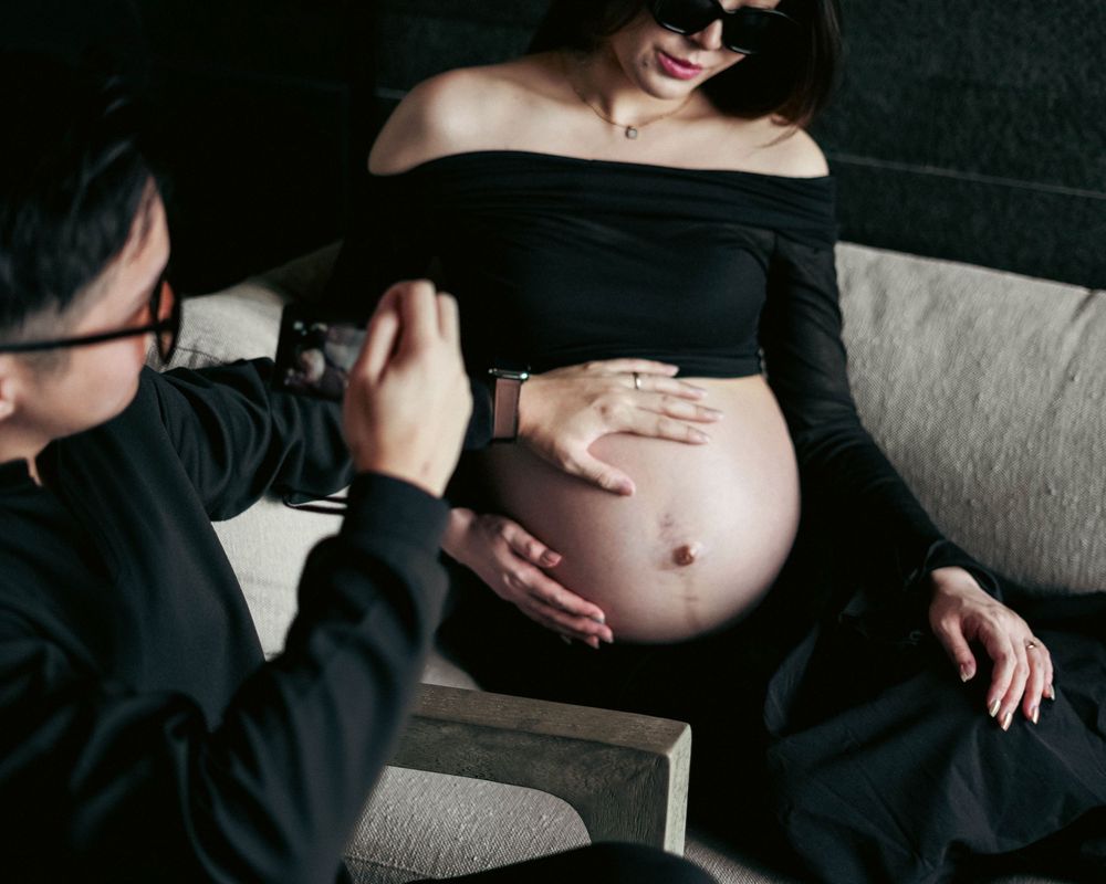 A maternity photoshoot shows a pregnant belly while someone takes a photograph.