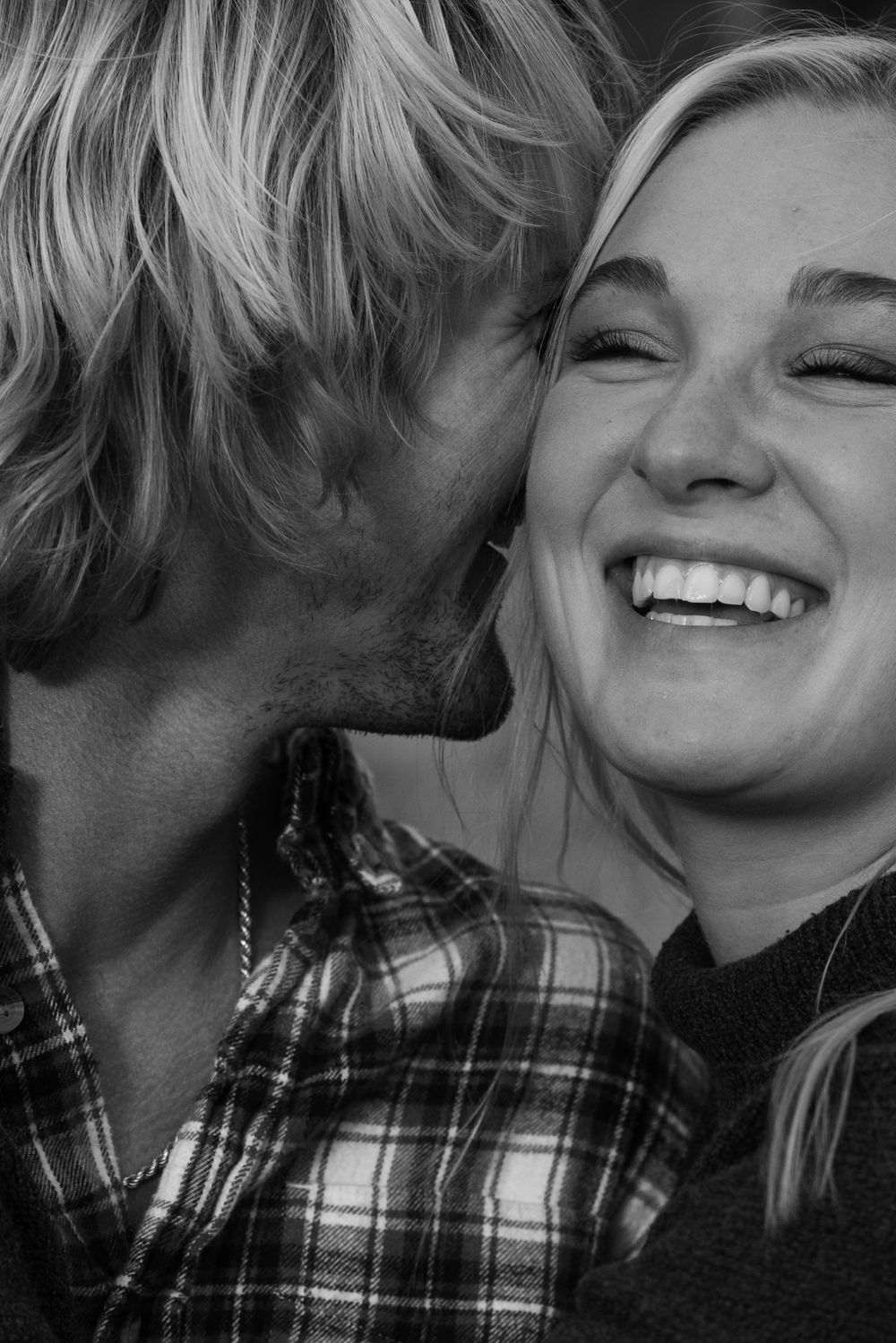 A black and white candid photo showing a joyful intimate moment between two people sharing laughter.