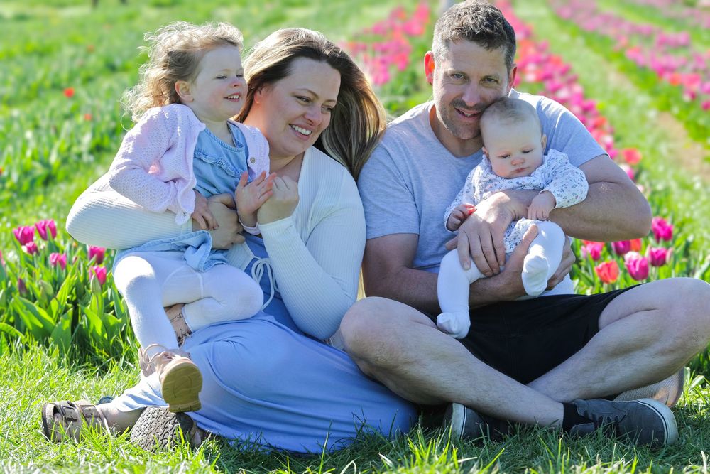 Family sitting together in a field of blooming spring flowers on a sunny day.