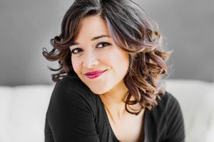 Lifestyle portrait featuring soft waves and natural makeup against light background.