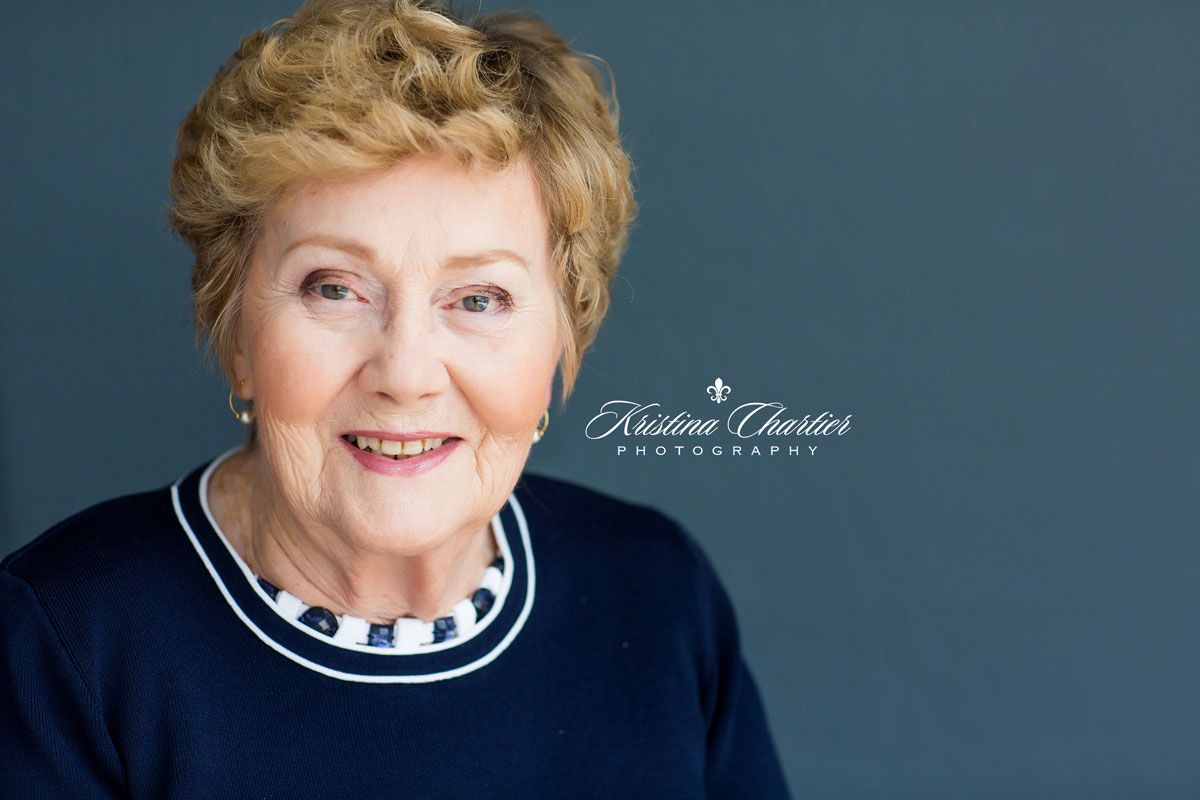 Professional portrait against blue background wearing navy and white striped collar.